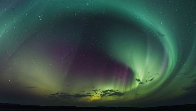 Aurora borealis swirling over remote northern plain, northern lights in green teal purple curtains