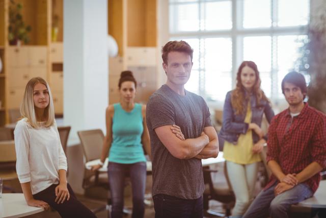 Group of young business professionals standing confidently in a modern office environment. Ideal for use in articles or advertisements related to teamwork, startup culture, modern workspaces, and business collaboration.