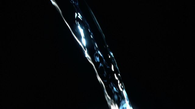 This video shows a close-up view of a trickle of water flowing in super slow motion, with a blue glint highlighting its fluid nature against a black background. The detailed capture of water makes it ideal for use in environmental articles, visual arts and design projects, or advertisements for purity and cleanliness themes.