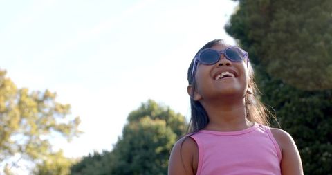 Joyful Young Girl in Pink Top Wearing Sunglasses Outdoors