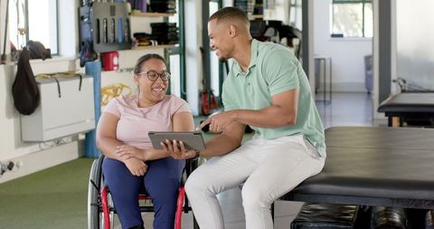 Rehabilitation Therapist Engaging Woman in Wheelchair with Tablet Interaction