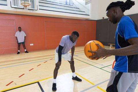Fast-paced basketball drill with african american teammates practicing defense on court