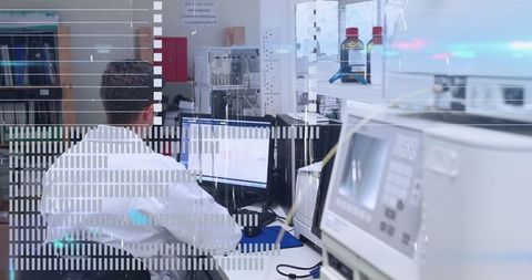 Lab technician analyzing data on computer monitors in high-tech laboratory