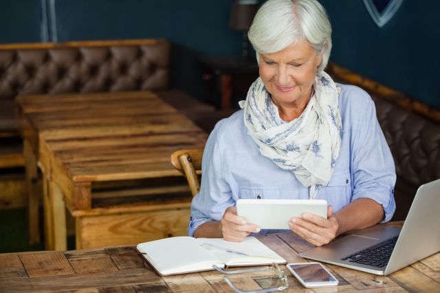 Smiling Senior Woman Using Digital Tablet in Cafe - Download Free Stock Images Pikwizard.com