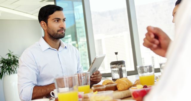 Businessman Attending Breakfast Meeting, Holding Tablet, Engaging with Colleagues - Download Free Stock Images Pikwizard.com