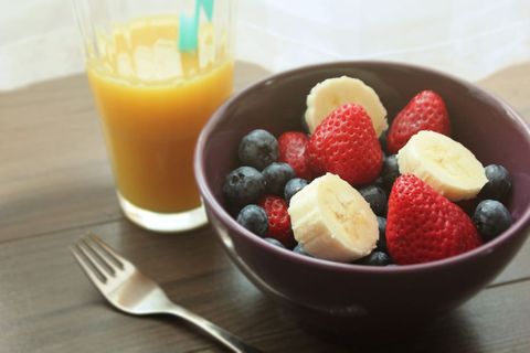 Serving Fresh Fruit Bowl with Strawberries Blueberries and Banana beside Orange Juice