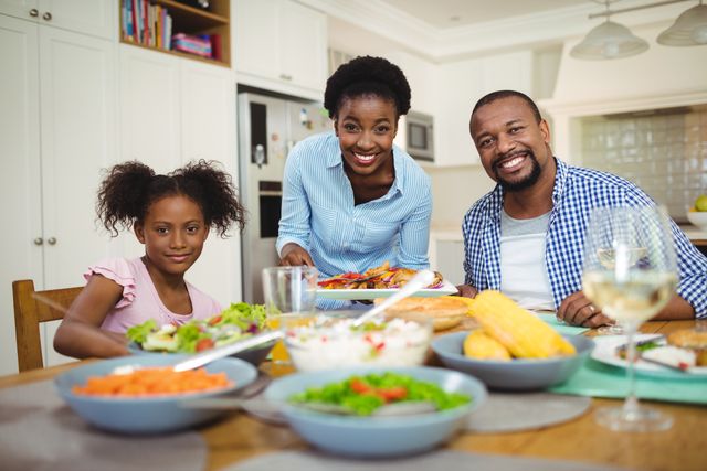 Family enjoying a meal together at home. Perfect for use in advertisements, articles, and blogs about family life, home-cooked meals, and healthy eating. Can also be used for content related to parenting, family bonding, and domestic happiness.