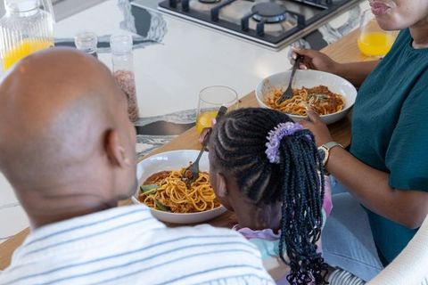 African american family sharing spaghetti at kitchen counter enjoying cozy mealtime