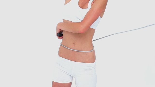 This video depicts a woman in white sportswear swinging a skipping rope. It is perfect for use in health and fitness promotions, blog posts about workout routines, advertisements for sports clothing or equipment, and articles focused on active lifestyles.