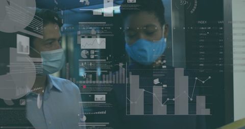 Diverse professionals analyzing data with covid-19 precautions in office