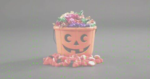 Halloween jack-o'-lantern candy bucket brimming with foil treats spilling candy corn