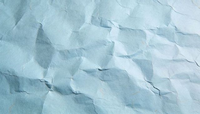 Crumpled Light Blue Paper Texture with Creases and Brown Flecks for Background Use Closeup