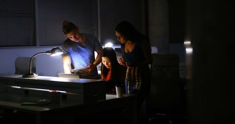 Coworkers Collaborating on Project Late at Night in Office