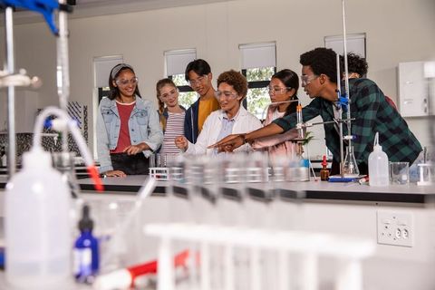 High school students and instructor conducting chemistry experiment in modern science lab