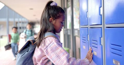 Young Biracial Girl Opening Locker in School Hallway
