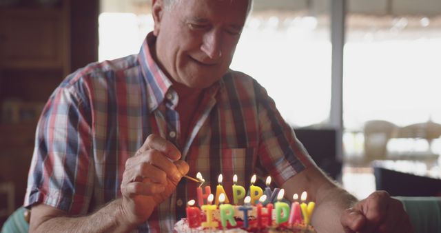 Caucasian senior man with birthday cake at home. Retirement, senior lifestyle, happiness, domestic life, birthday, celebration and wine making, unaltered.