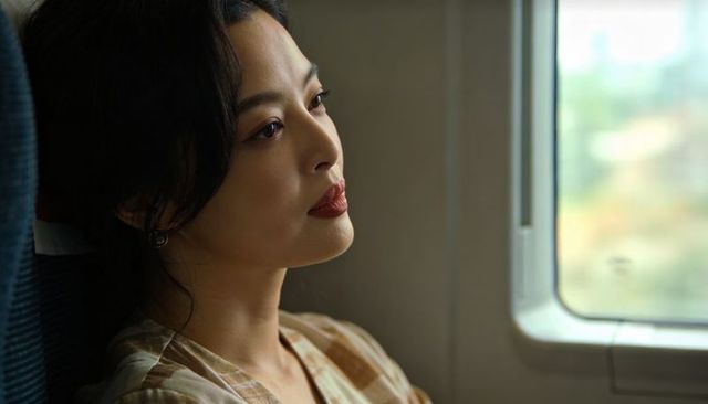 Contemplative asian woman gazing out train window during serene commute, natural light