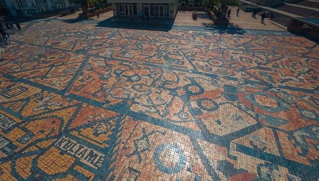 Aerial mosaic plaza pattern covering urban public forecourt geometric terracotta blue tiles