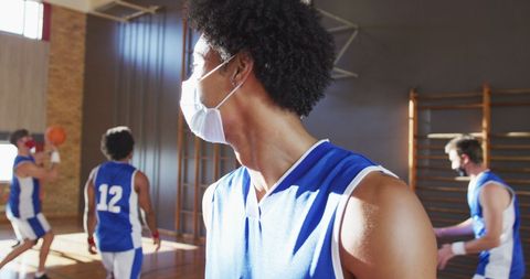 Masked basketball players practicing indoors during pandemic