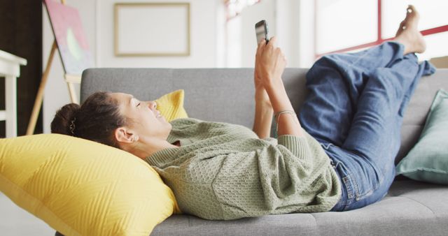 Relaxed woman scrolling on smartphone while laying on couch - Download Free Stock Images Pikwizard.com