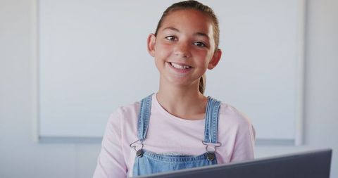Smiling Student in Classroom Wearing Denim Overalls