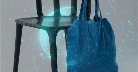 Hanging blue canvas tote bag showing creases next to chair with holographic globe overlay
