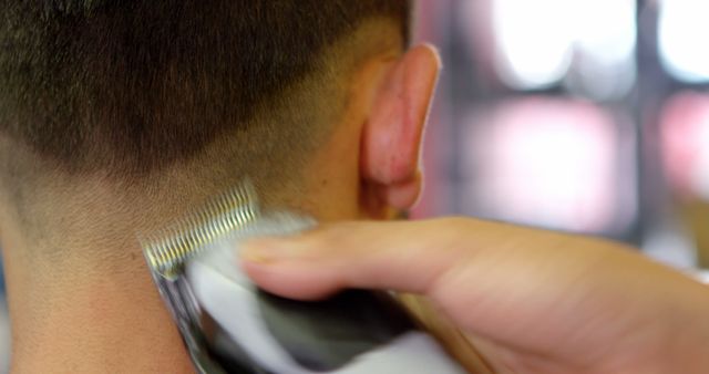 Close-up of barber using clippers to trim a man's short hair, focusing on back of the neck. Ideal for content related to grooming, hairstyling, barber services, or hair care tutorials.