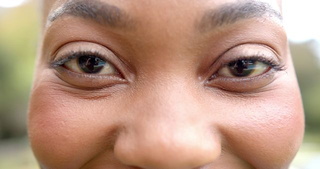 Eyes of happy african american woman standing and smiling in sunny garden. Relaxation and free time, wellbeing, unaltered.