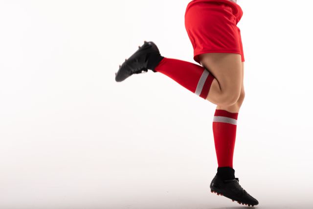 This image captures the dynamic movement of a female soccer player in mid-kick, showcasing her red uniform and cleats. Ideal for use in sports-related content, advertisements for athletic wear, or promotional materials for soccer events and competitions.