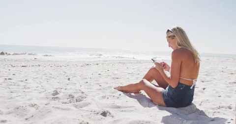 Relaxed Woman Browsing Smartphone on Sunny Beach