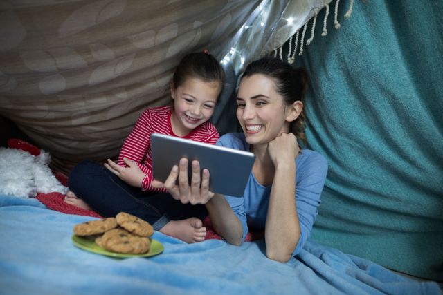 Mother and daughter using digital tablet while playing at home