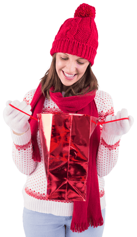 Smiling woman in winter attire opening transparent holiday gift bag