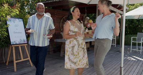 Outdoor 60th birthday celebration with friends dancing, laughing, serving desserts