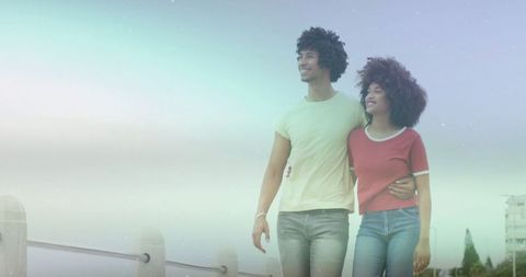 Smiling Couple Walking Along Waterfront Promenade in Casual Outfits