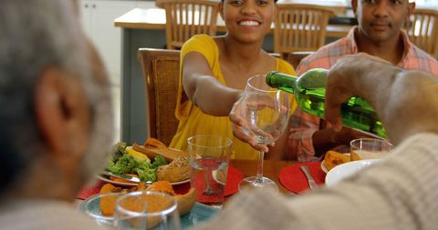 Family Enjoying Meal Together with Wine Pouring at Home