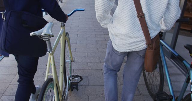Young adults are casually walking with their bicycles on an urban sidewalk, engaging with the city environment. Suitable for urban lifestyle themes, transportation visuals, and youth-oriented content.
