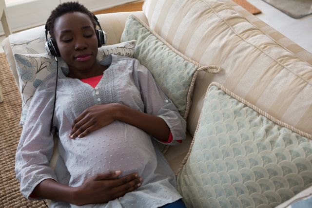 Pregnant Woman Relaxing with Headphones on Couch - Download Free Stock Photos Pikwizard.com