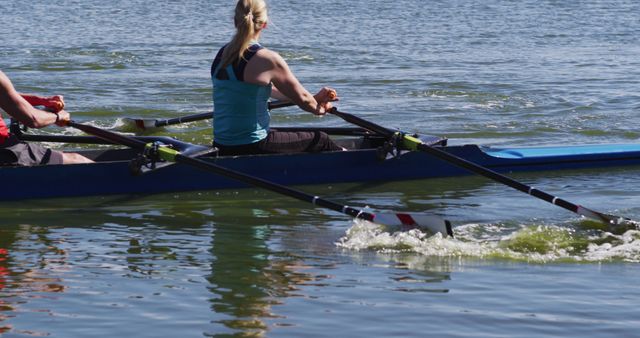A couple engaged in synchronized rowing on a clear water lake, emphasizing athletic teamwork and outdoor fitness. Perfect for sports event advertisements, fitness promotions, teamwork concepts, and active lifestyle campaigns.