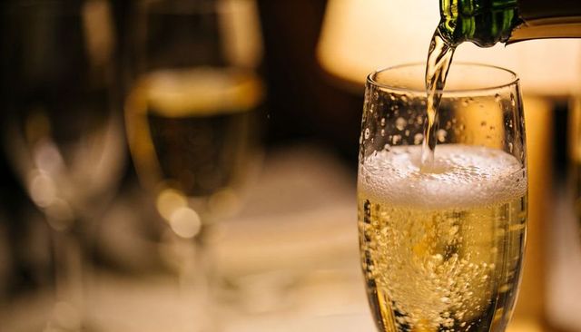 Pouring champagne into flute under warm candlelight for romantic celebration