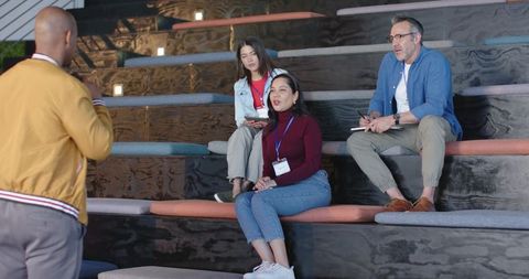 Diverse team listening during informal presentation on tiered seating at workshop