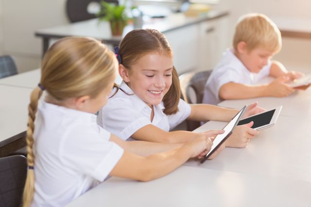 This image showcases school children using digital tablets in a classroom environment. It is ideal for illustrating modern education, technology in schools, student engagement, and collaborative learning activities. Perfect for educational blogs, websites, brochures, and advertisements promoting digital learning tools.