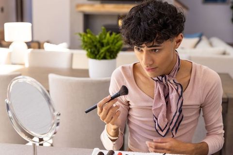 Man Applying Makeup with Brush and Mirror at Home