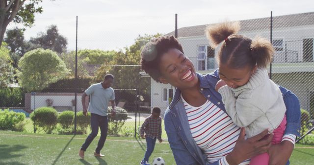Portrait of happy african american family playing football in park. Spending quality time with family outdoors concept.