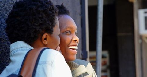 Twin African Sisters Laughing and Gossiping in Urban Environment