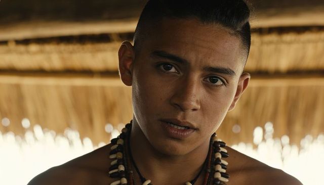 Shirtless teen male portrait wearing shell bead necklaces under thatched palapa sunlit mood