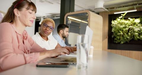 Modern Diverse Team Collaborating on Laptops at Office Desk