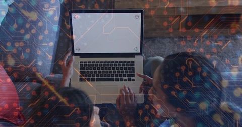 Mother and teen daughter sharing laptop and pointing at blank screen with circuit overlay