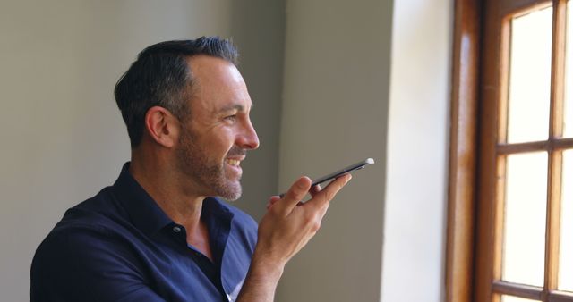 Happy Man Using Voice Command on Smartphone Near Window - Download Free Stock Images Pikwizard.com