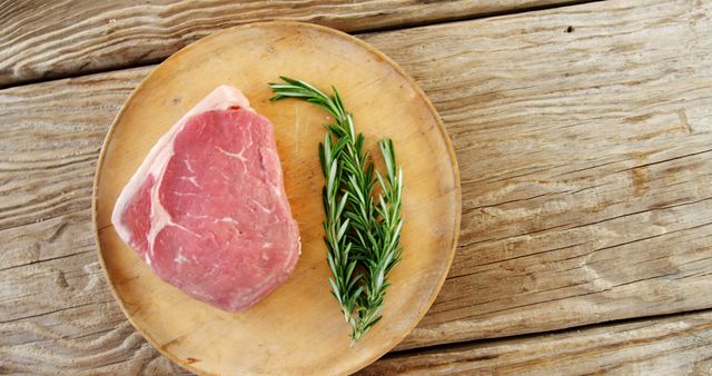 Raw pork chop with fresh rosemary on wooden plate - Download Free Stock Images Pikwizard.com