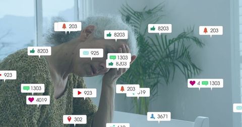 Senior woman overwhelmed by digital notifications at home desk